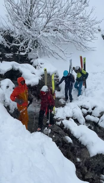 Groupe en ski de randonnée traversant un cours d'eau enneigé avec un guide dans les montagnes du Val d'Aran, Encantats.