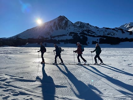 Groupe de skieurs de randonnée avançant sur une étendue plate enneigée en direction du Petit Péric.