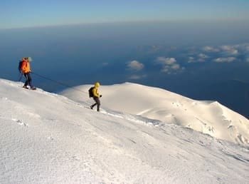 Deux alpinistes encordés en train de redescendre un sommet enneigé, après l'avoir gravi, laissant des traces dans la neige fraîche. Deux alpinistes encordés en train de redescendre un sommet enneigé, après l'avoir gravi, laissant des traces dans la neige fraîche.