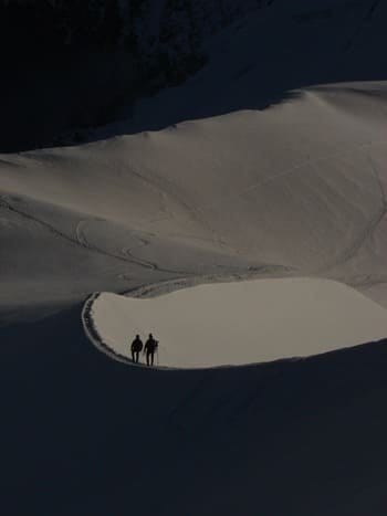 Deux alpiniste redescendant de leur sommet à l'ombre dans un décors immaculé de neige. Deux alpiniste redescendant de leur sommet à l'ombre dans un décors immaculé de neige.