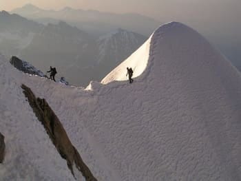 Alpiniste marchant le long d'une crête enneigée, équipé pour l'ascension. Alpiniste marchant le long d'une crête enneigée, équipé pour l'ascension.