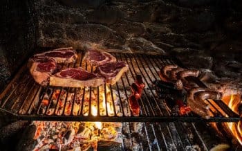 Grillades d'entrecôtes et saucisses sur le feu de cheminée dans le restaurant du refuge de Montgarri, Val d'Aran, Espagne, lors d'une pause culinaire pendant un raid à ski. Grillades d'entrecôtes et saucisses sur le feu de cheminée dans le restaurant du refuge de Montgarri, Val d'Aran, Espagne, lors d'une pause culinaire pendant un raid à ski.