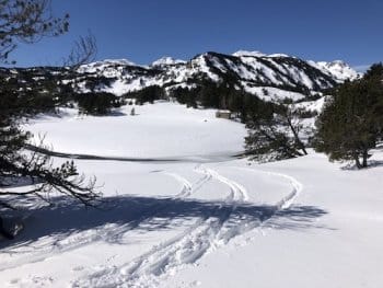 Descente à ski de randonnée dans la vallée du Galbe près de Font-Romeu, au départ de Formiguères, lors d'un raid, avec des traces de skis dans la neige, au milieu d'un paysage de sapins enneigés et de sommets, et une cabane en pierre visible au loin. Descente à ski de randonnée dans la vallée du Galbe près de Font-Romeu, au départ de Formiguères, lors d'un raid, avec des traces de skis dans la neige, au milieu d'un paysage de sapins enneigés et de sommets, et une cabane en pierre visible au loin.