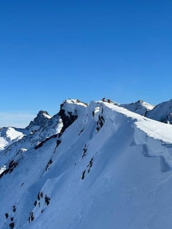 Deux alpinistes avec skis de randonnée sur le dos franchissent une crête pour atteindre un sommet dans le parc naturel du Queyras lors d'un raid à ski, illustrant l'aventure alpine accompagné d'un guide de haute montagne. Deux alpinistes avec skis de randonnée sur le dos franchissent une crête pour atteindre un sommet dans le parc naturel du Queyras lors d'un raid à ski, illustrant l'aventure alpine accompagné d'un guide de haute montagne.