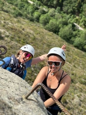 Deux copines souriantes en haut de la via ferrata de Llo dans le 66 avec un guide de haute montagne Deux copines souriantes en haut de la via ferrata de Llo dans le 66 avec un guide de haute montagne