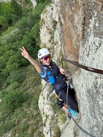 Participante joyeuse accrochée au câble de la via ferrata dans les Pyrénées Participante joyeuse accrochée au câble de la via ferrata dans les Pyrénées